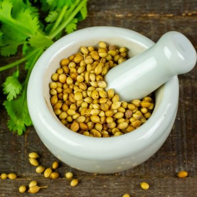 Coriander,Seeds,On,White,Mortar,And,Pestle,With,Green,Leaf